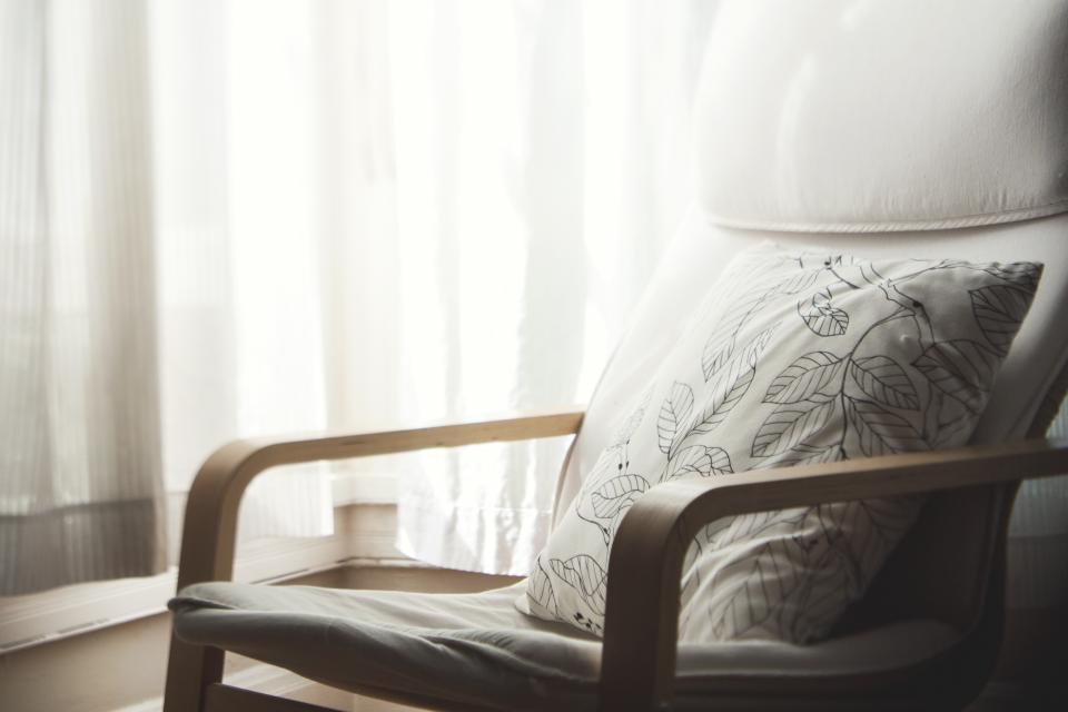 Armchair with a cushion beside a sunlit window