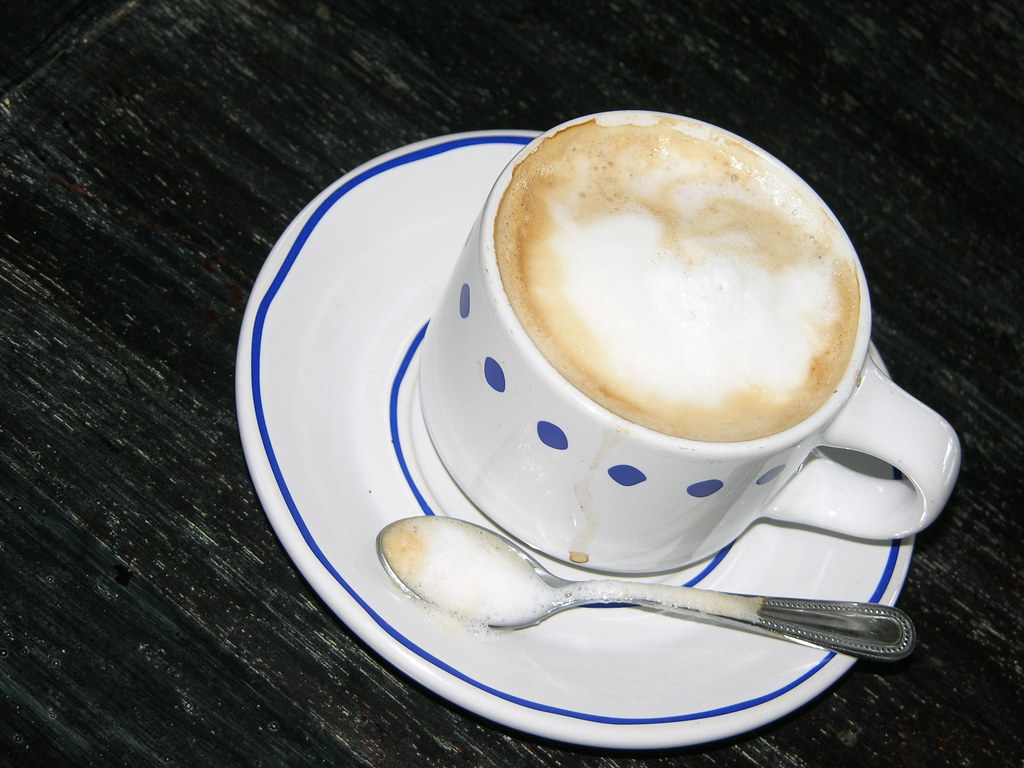 Latte with milk foam in a white cup on a saucer