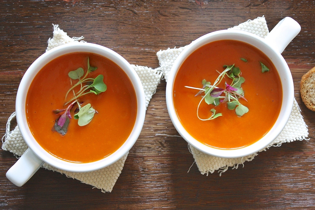 Two bowls of tomato soup on a wooden table